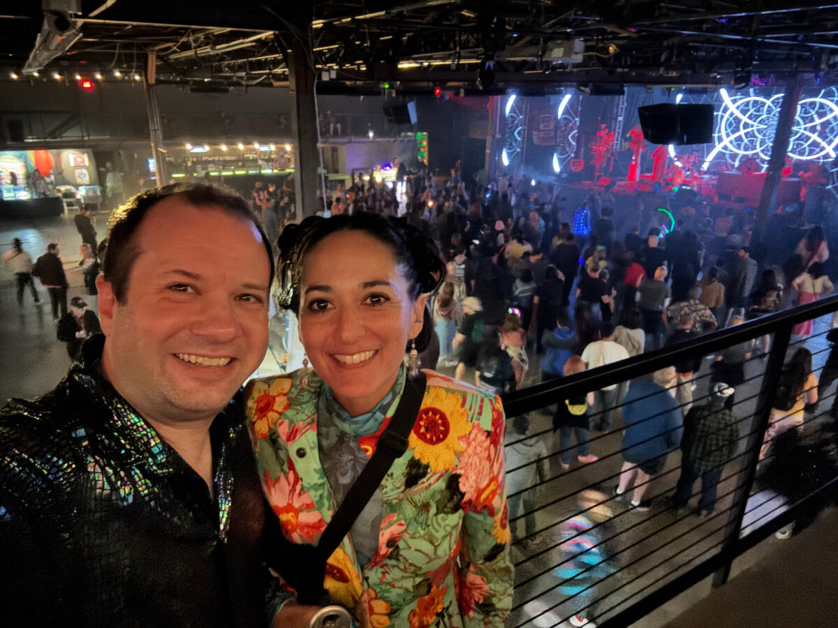 Michael and Michelle selfie inside a dance club, taken from the second floor with a view of the main floor beneath/behind them.